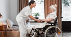Support worker holding hands with a woman in a wheelchair.