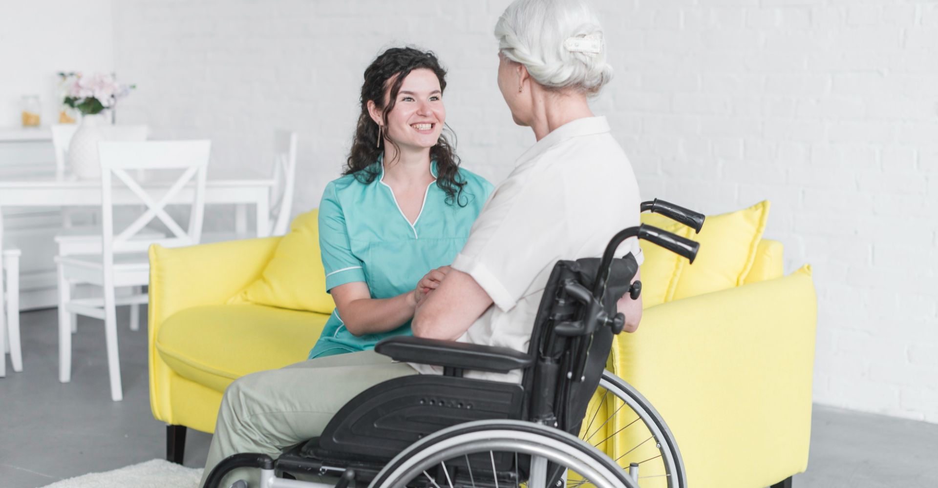 Support worker in green scrubs talking with a woman in a wheelchair