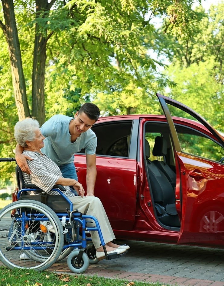 Personal travel and transportation support helping a senior into a red vehicle